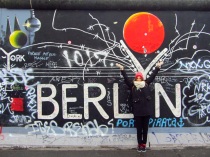 Pili in front of a graffiti on the wall, East Side Gallery, Berlin